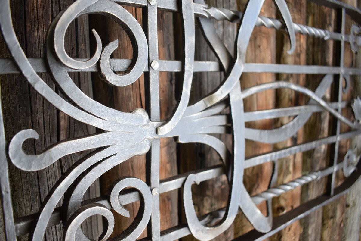 Detail ručně kované okenní mříže inspirované přírodou. Vyrobeno pomocí tradičních kovářských technik. Moderní dům, luxusní vila. 