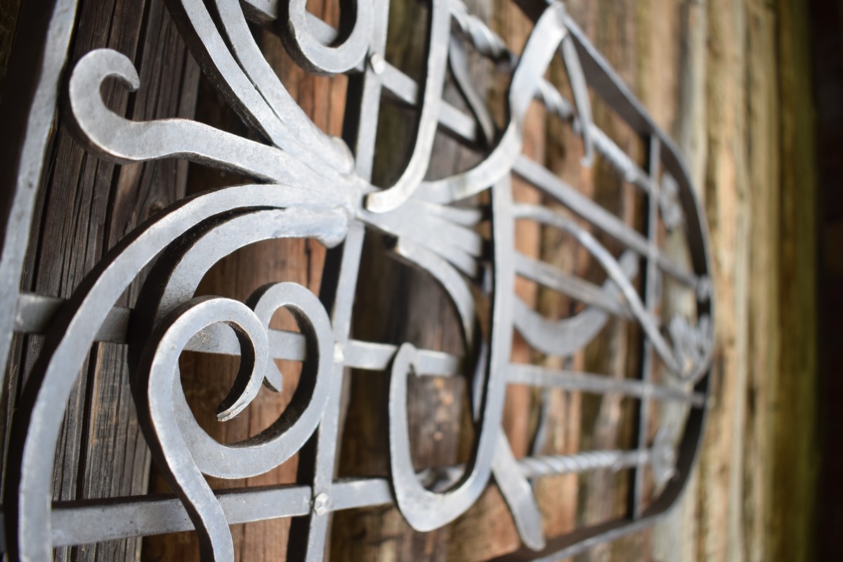 Detail kované okenní mříže s přírodním motivem květiny.  Tradiční výrobní technika. Stylová vila. moderní dům.